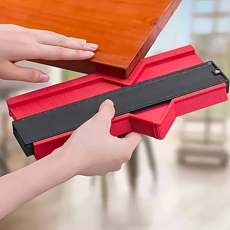 Hands are using a red plastic contour measuring ruler to measure or mark a surface.