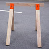 Holzwerkbank mit robusten Metallhaltern und orangefarbenen Akzenten.