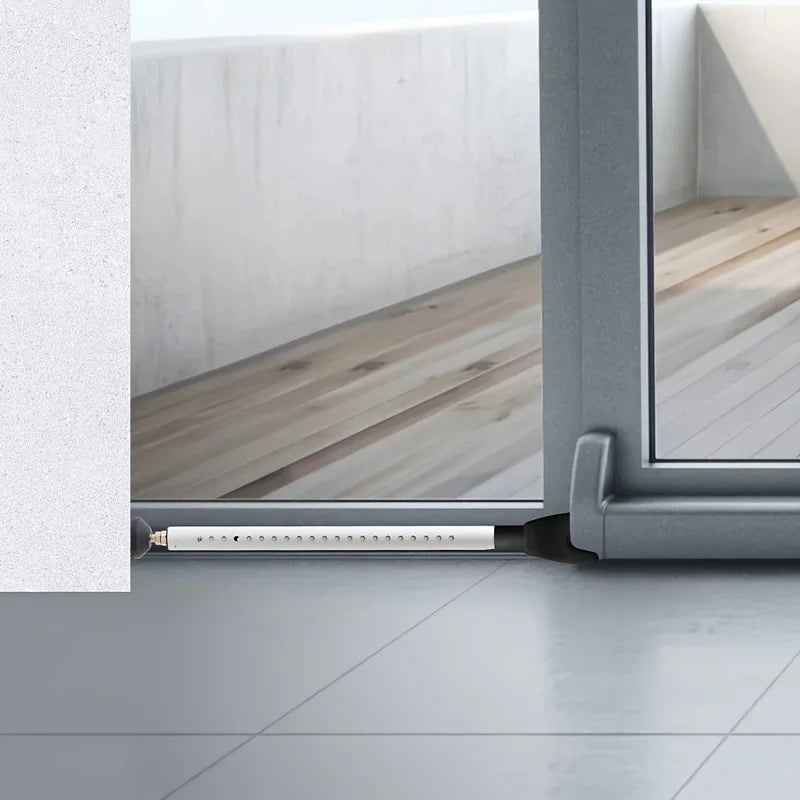 A close-up view of an adjustable portable door security bar installed in a window frame.
