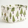 A light linen storage basket with a green and brown pine tree pattern.