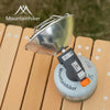 A silver portable butane camping stove with a protective cover rests on a wooden surface.