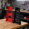 A red plastic wrench organizer rack is displayed on a wooden workbench in a workshop setting.