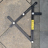 A black precision six-fold construction angle measuring ruler is shown angled on a gray tiled surface.