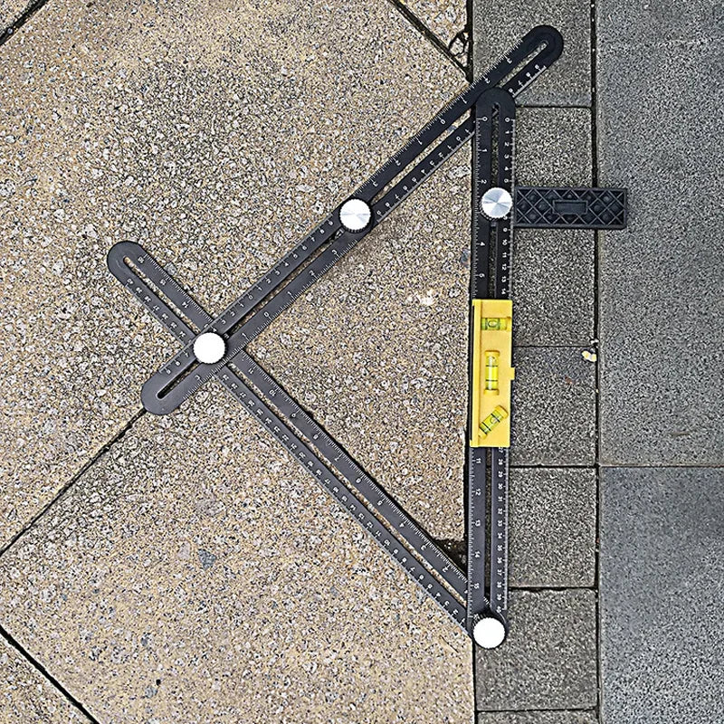 A black precision six-fold construction angle measuring ruler is shown angled on a gray tiled surface.