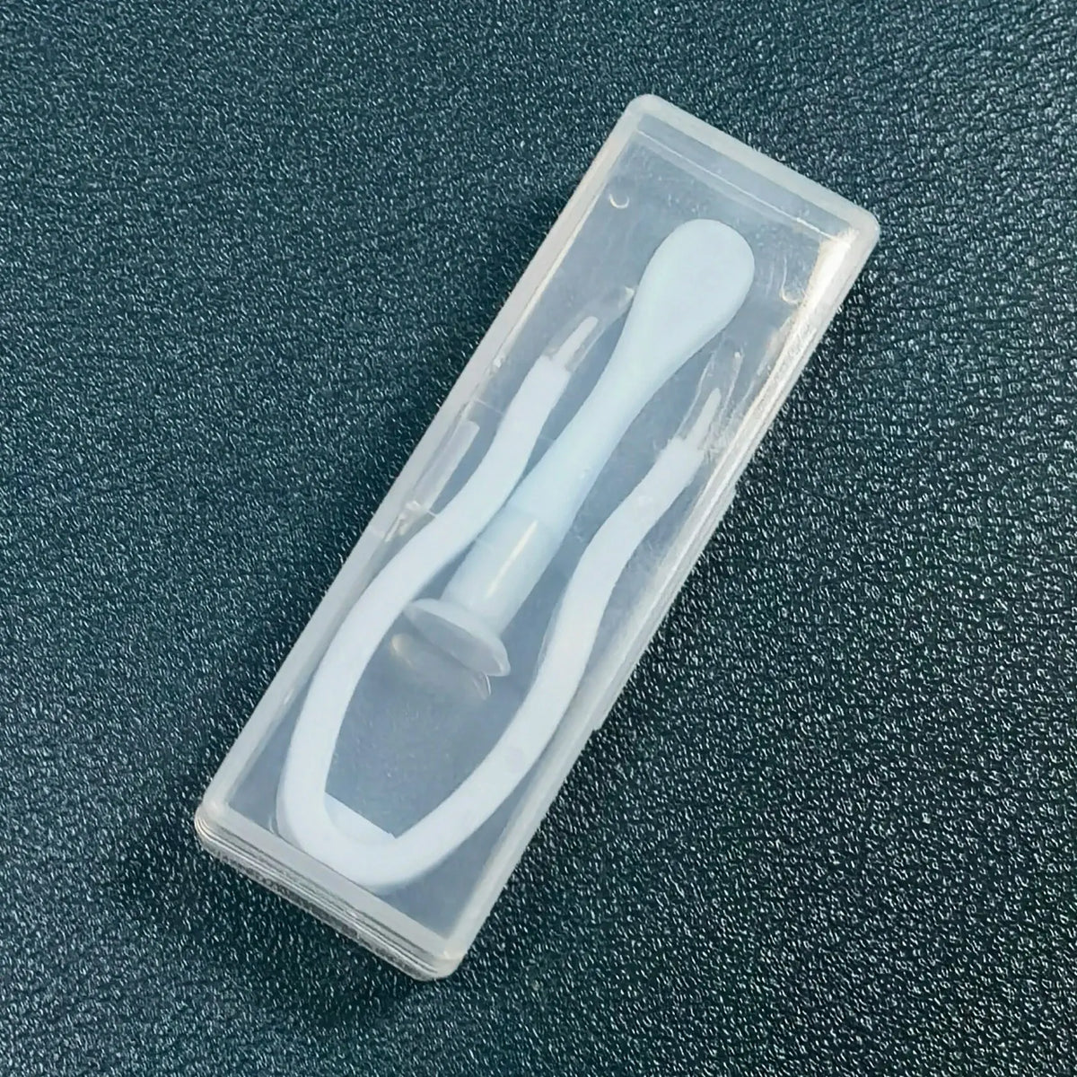 A clear plastic case containing a white contact lens tool kit with multiple instruments.