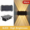 Schwarze Solarlampe mit Solarmodul, die eine Wand mit warmem gelbem Licht beleuchtet.