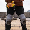 A person wearing dark pants is holding a yellow power tool and displaying gray Zeluga knee pads.