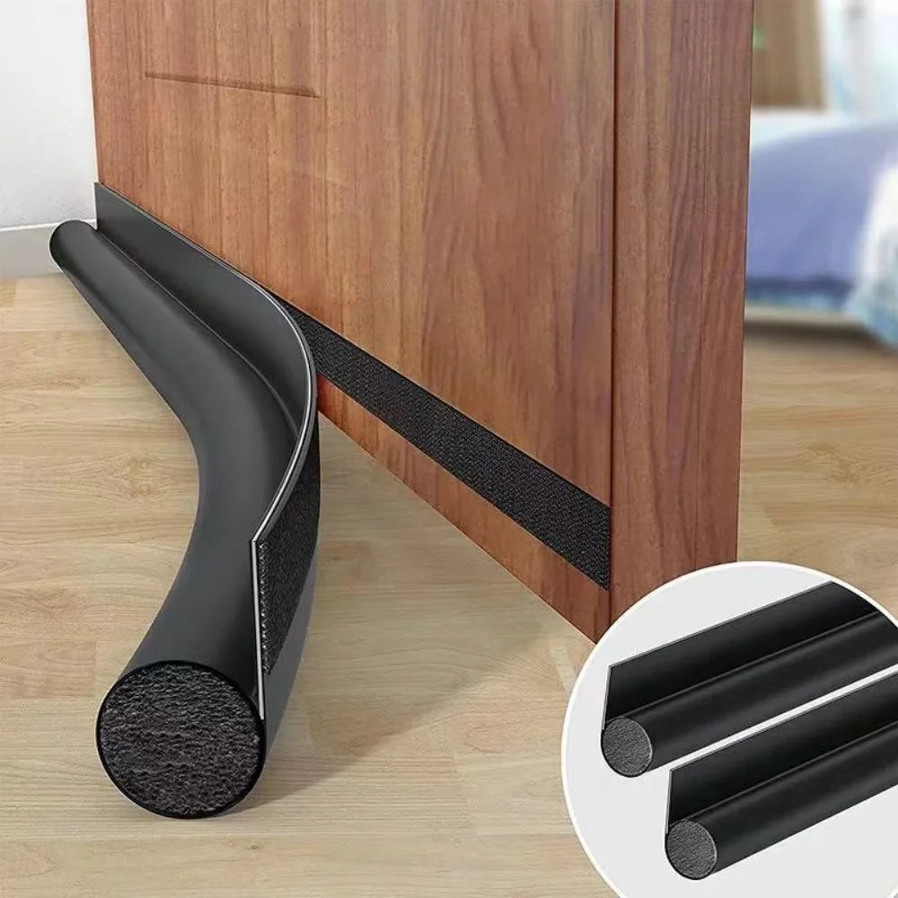 Topetador de puerta ajustable negro para sellar corrientes de aire en una puerta de gabinete de madera.