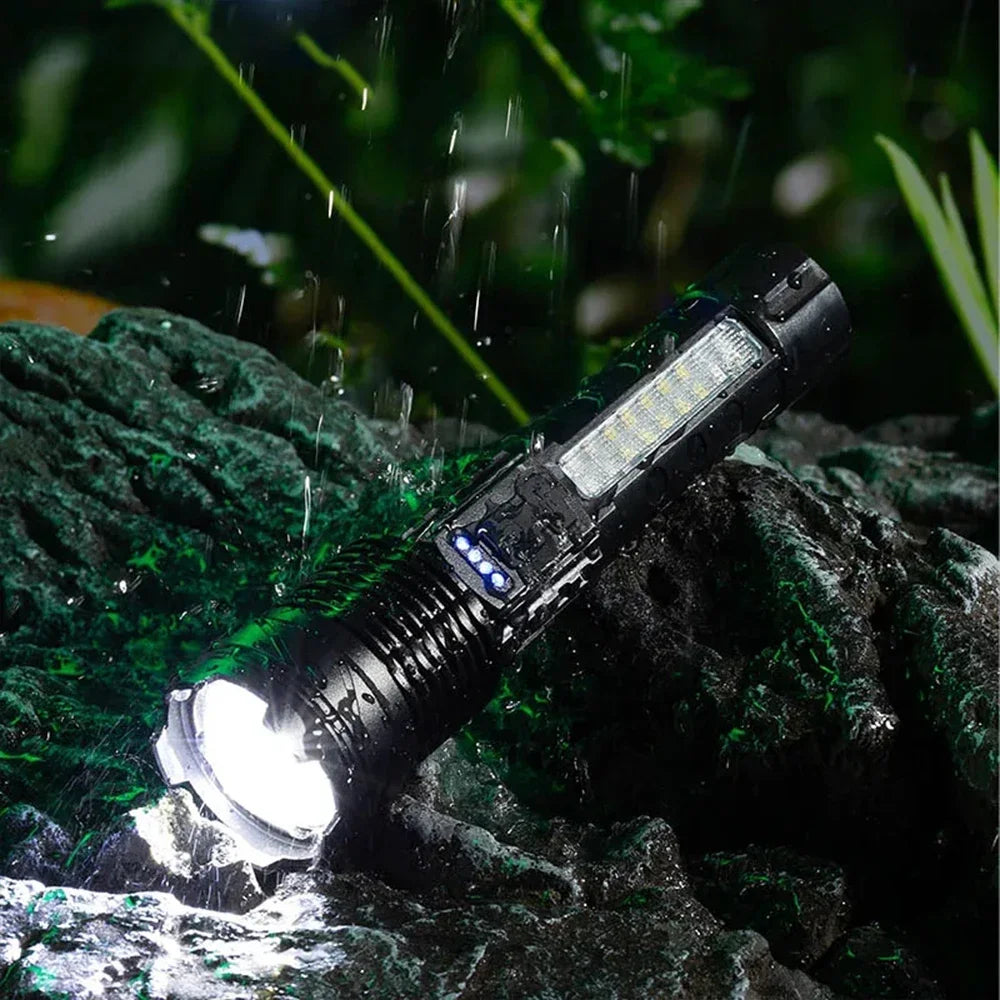 A black tactical LED flashlight is shown illuminating a wet, dark rock surface amidst falling rain.