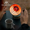 A hand holds a portable butane camping stove with a visible flame, set against a dark background.