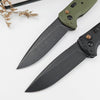 A folding utility knife with a green handle and black blade resting on a white surface.
