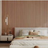 A bedroom featuring a wooden slat wall, a bed with white linens and beige accents, and a bedside table.