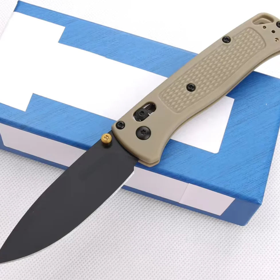 Un couteau pliable beige avec une lame noire posé sur une boîte bleue.