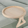A round wooden tray with a stand is placed on a light green sofa cushion.
