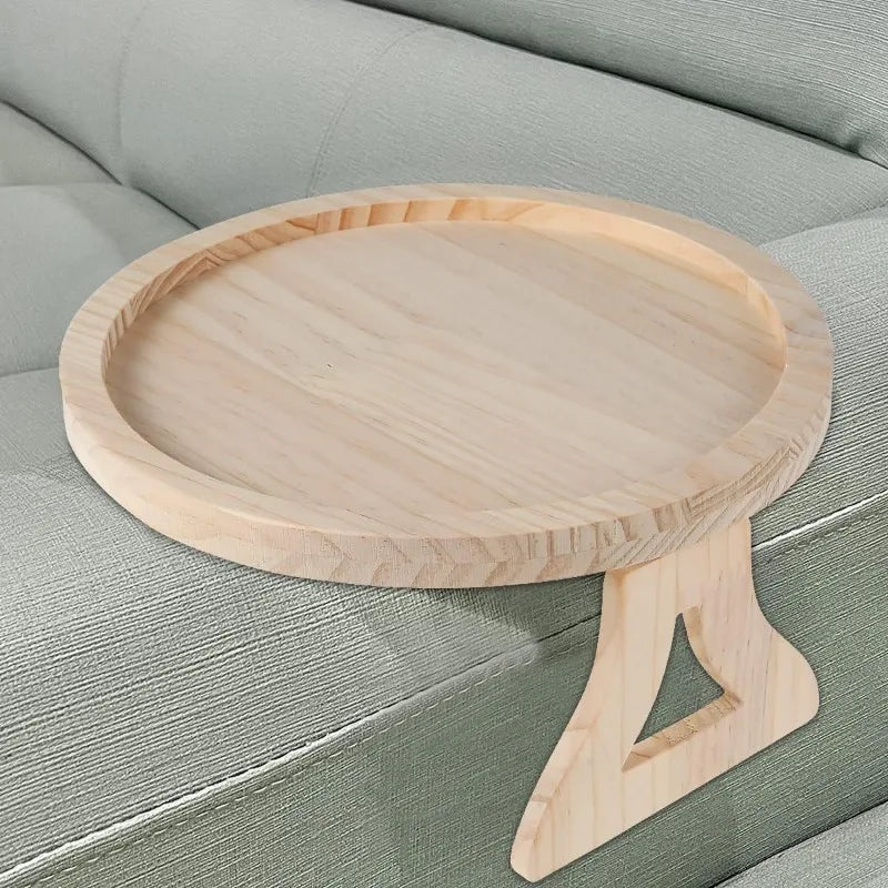 A round wooden tray with a stand is placed on a light green sofa cushion.