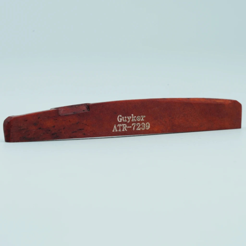 A wooden guitar bone bridge saddle with the inscription GUYKOV ATR-7239
