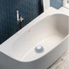 A white, oval bathtub with a circular drain protector installed in a modern bathroom setting.