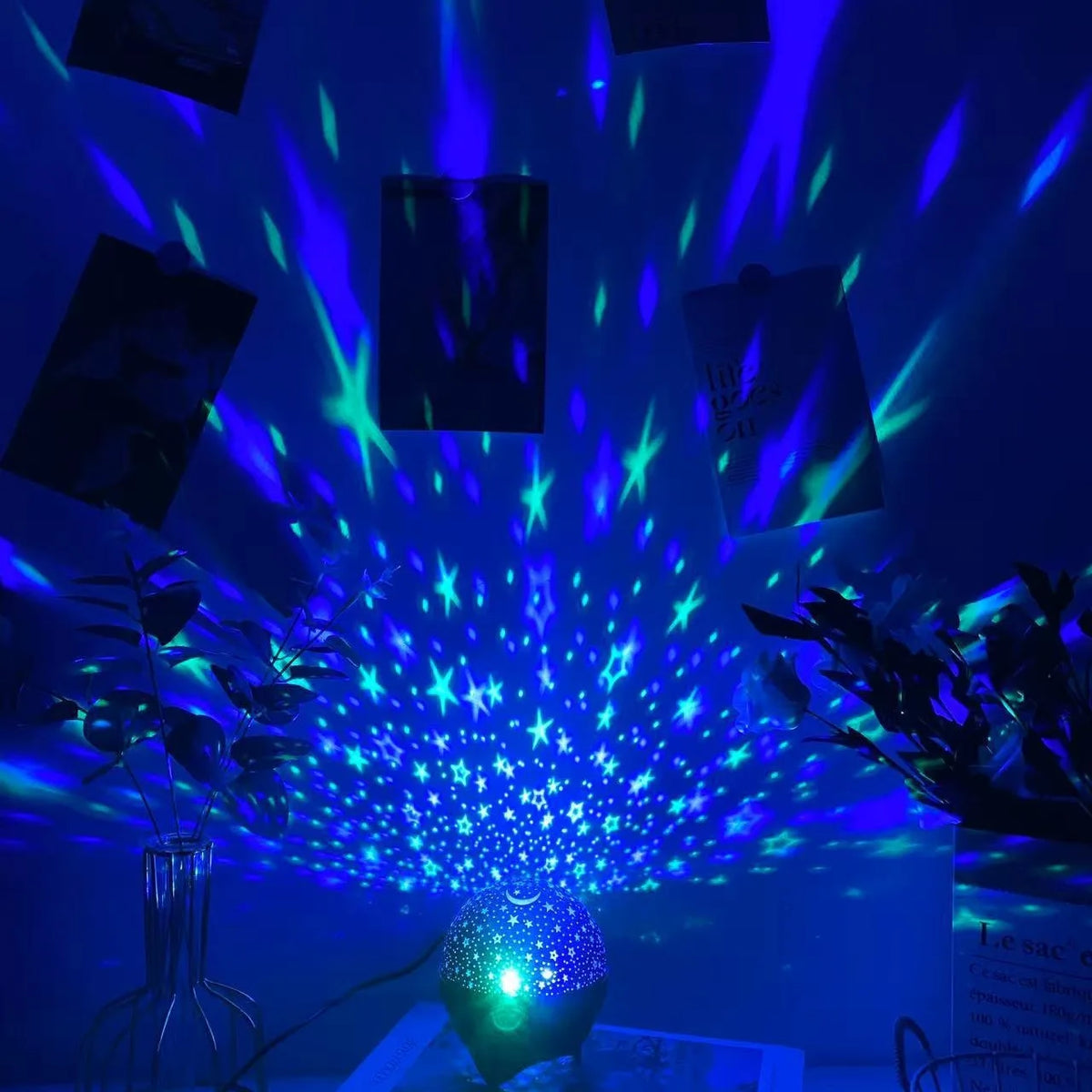 A galaxy projection night light illuminates a dark room with bright blue and green star-like beams.