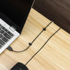 A black computer mouse and cable clips are shown on a light wooden desk surface.
