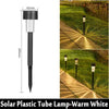 A black solar plastic tube lamp mounted on a stake, illuminating an outdoor pathway.