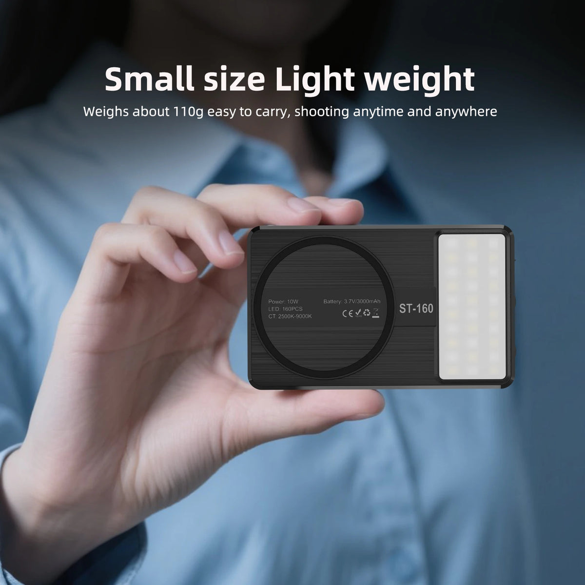 Une main tient un panneau lumineux noir compact à LED avec une lumière blanche, montrant sa petite taille et sa portabilité.