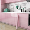 A kitchen cabinet featuring glossy pink marble contact paper and a sink area with stainless steel fixtures.