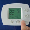 A white digital thermostat displaying 82 degrees inside and 78 degrees heat setting.