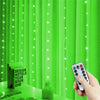 يد تمسك بهاتف يعرض أضواء خيطية LED تضيء ستائر خضراء عمودية ساطعة.