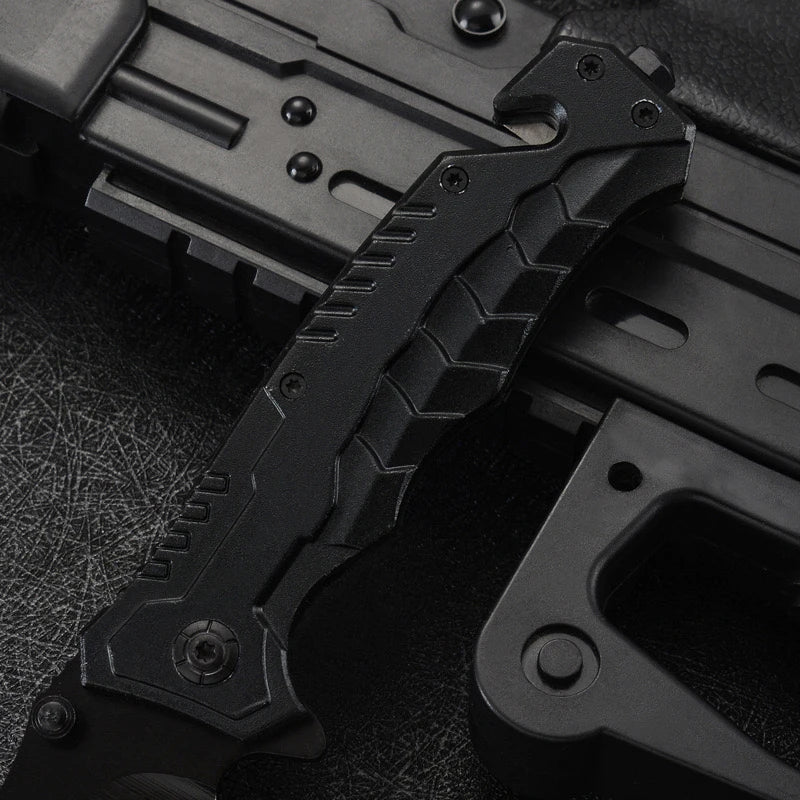 A close-up view of a black outdoor folding utility knife with a textured handle and blade visible.