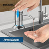 A hand is pressing down on a stainless steel soap dispenser extension tube to dispense liquid into a sink.