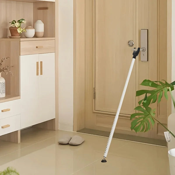 A white adjustable portable door security bar is shown next to a light wood cabinet and a beige door.