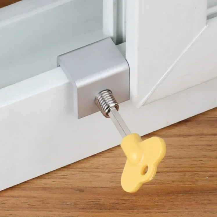 A yellow sliding window sash lock stopper is shown mounted on a white window frame.