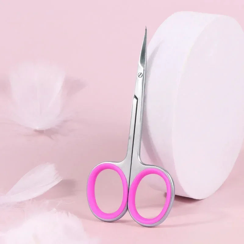 A pair of pink-handled professional stainless steel nail cuticle trimmers resting on a pink background next to a white object