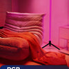 A pink room illuminated by a vibrant orange fabric and a vertical purple LED light bar.
