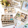 A collection of delicate jewelry, including rings and earrings, is displayed in various wooden storage trays and a silver fra