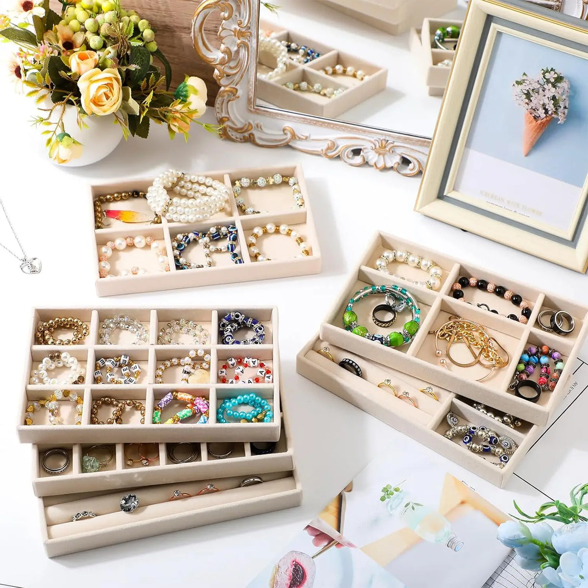 A collection of delicate jewelry, including rings and earrings, is displayed in various wooden storage trays and a silver fra