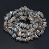 A circular arrangement of tumbled, translucent gray and blue-tinged agate beads for jewelry making.