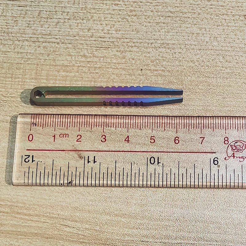 A titanium clip tweezers with a gradient finish is shown next to a ruler for scale.