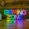 Letrero de LED de neón deletreando GAMING ZONE brillando en varios colores vivos sobre una superficie de madera.