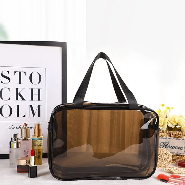 Klare Kosmetiktasche mit schwarzem Riemen neben verschiedenen Schönheitsprodukten.