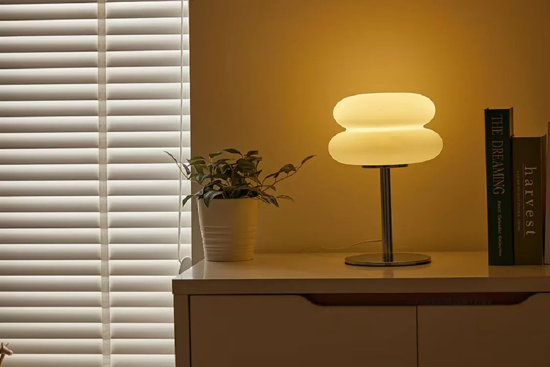 Lámpara de mesilla de noche ajustable en intensidad, estilo crema con pantalla redondeada, sobre una superficie de madera cla