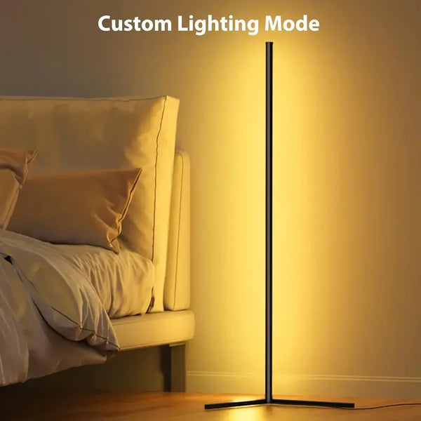 A tall, black floor lamp with a glowing yellow light illuminates a bedside area.