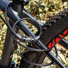 A close-up of a black portable anti-theft bike cable lock coiled around a bicycle frame.