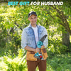 A man wearing a baseball cap and denim shirt holds a blue cordless mini chainsaw for wood cutting in an outdoor setting.