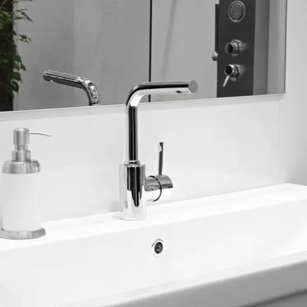 A modern chrome faucet mounted on a white bathroom sink with a reflection of a door and mirror.