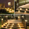 A row of outdoor deck steps illuminated by warm solar LED lights in a modern garden setting.