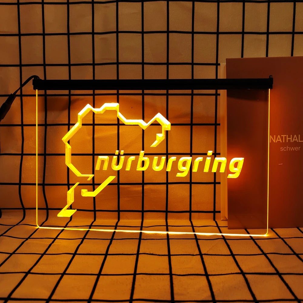 A glowing neon sign shaped like a stylized mountain silhouette spelling out Nürnbergring on a dark grid background.