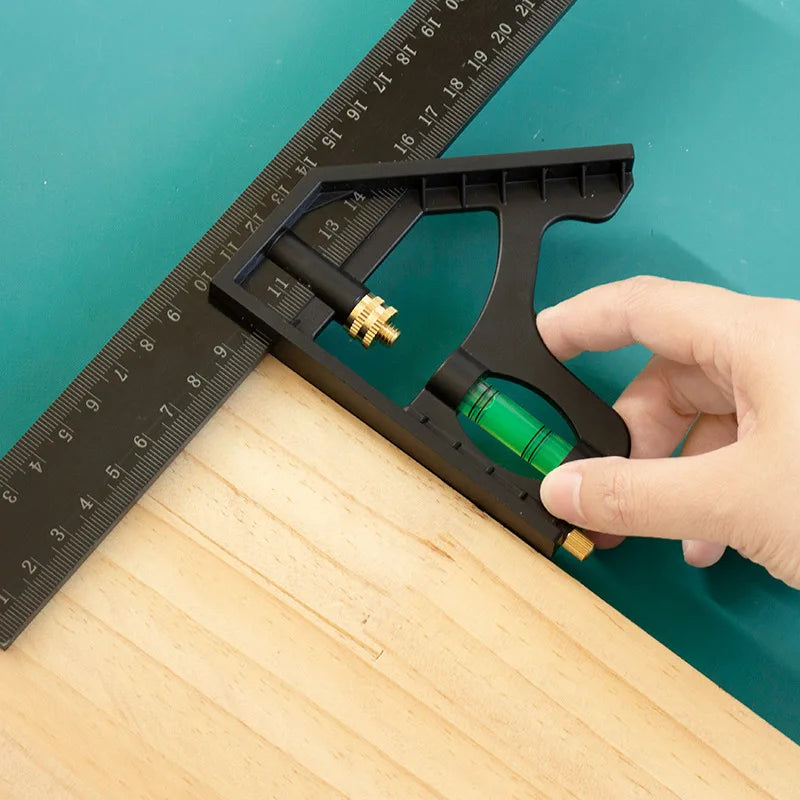 A hand holds a black precision measuring tool clamp against a wooden surface next to a ruler.