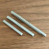 Two silver titanium clip tweezers lying on a wooden surface.