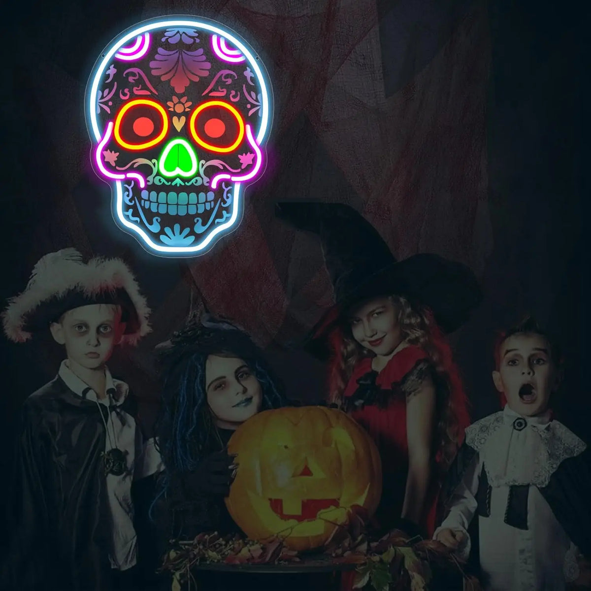 A group of children posing with a glowing neon skull sign and a carved pumpkin.